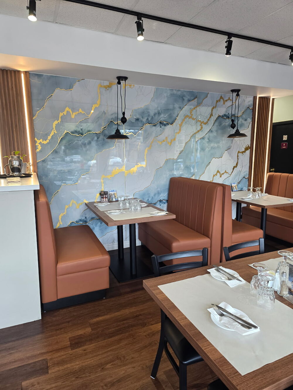 Tables set with white linens beneath framed artwork in the renovated dining room